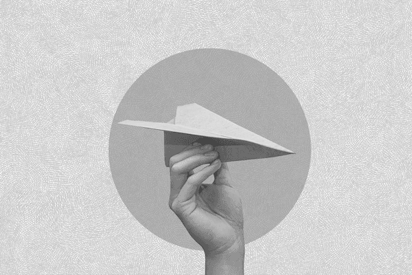 Hand holding a paper airplane in mid-air