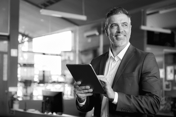 Man holding a tablet, smiling, looking off to the right