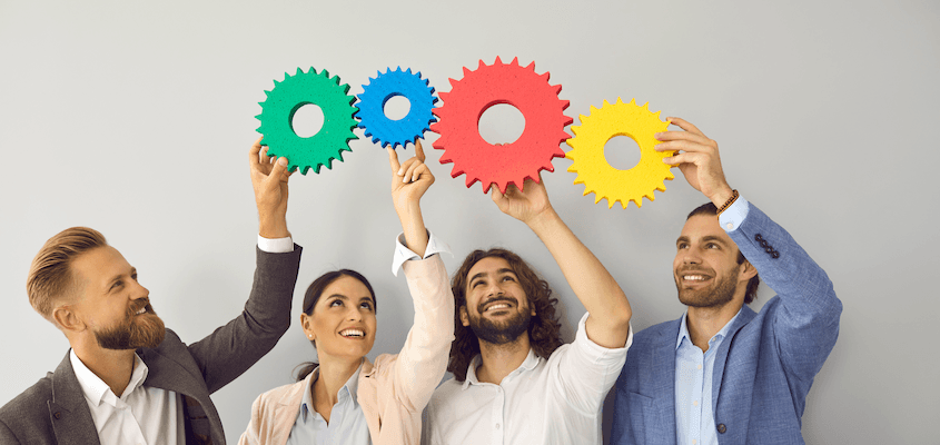 A team of three men and one woman holding up different coloured gearsimage | Featured image for the HSEQ Management System page for CertCrowd