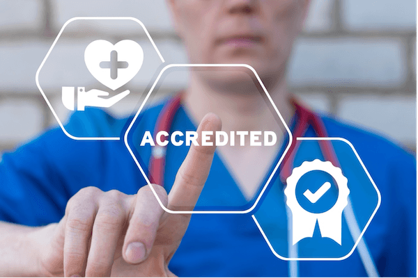 Doctor in the background tapping onto a hexagon shape with the word 'Accredited' in the middle, with two hexagons on either side with health and check icons
