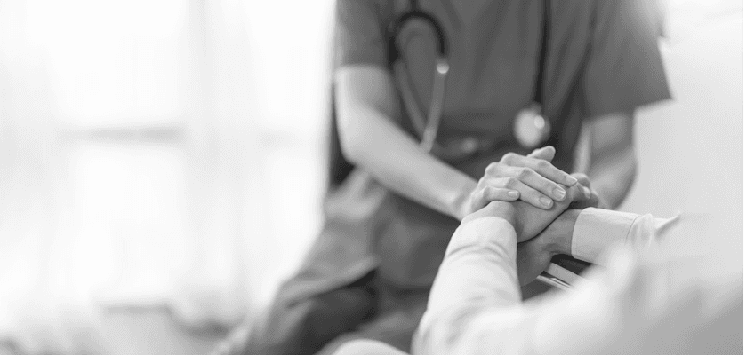 Healthcare professional holding the hands of a patient