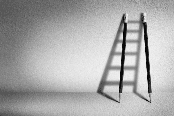 Black and white pencils with ladder shadow representing progress in ISO9001 certification