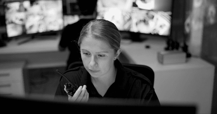 Woman holding a walkie talkie while looking at a monitor