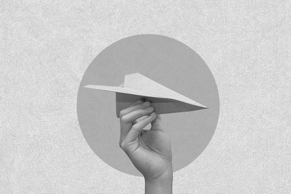 Hand holding a paper airplane in mid-air