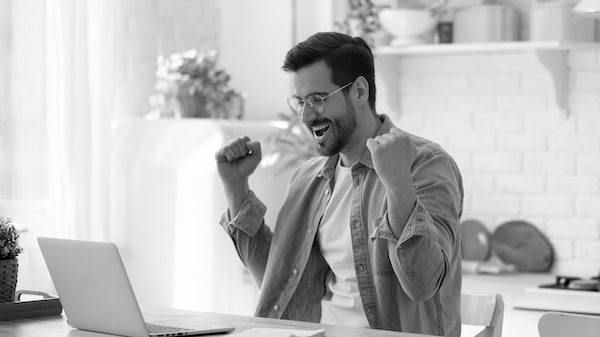 Man happy with hands up in air looking at laptop